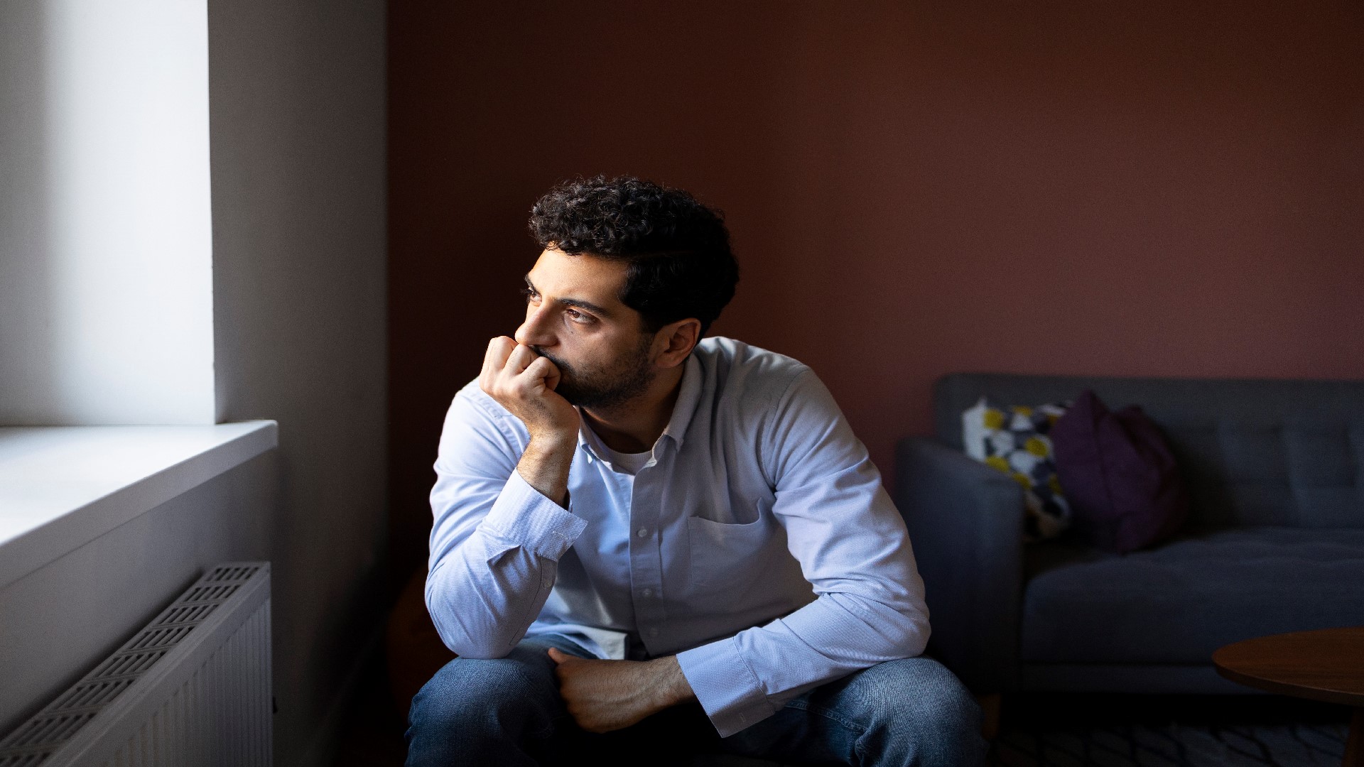 An Image of an anxious man looking outside a window