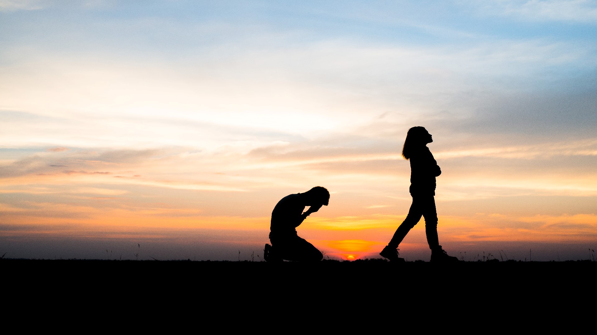 An Image of a womanl's silhoutte walking away from a Man